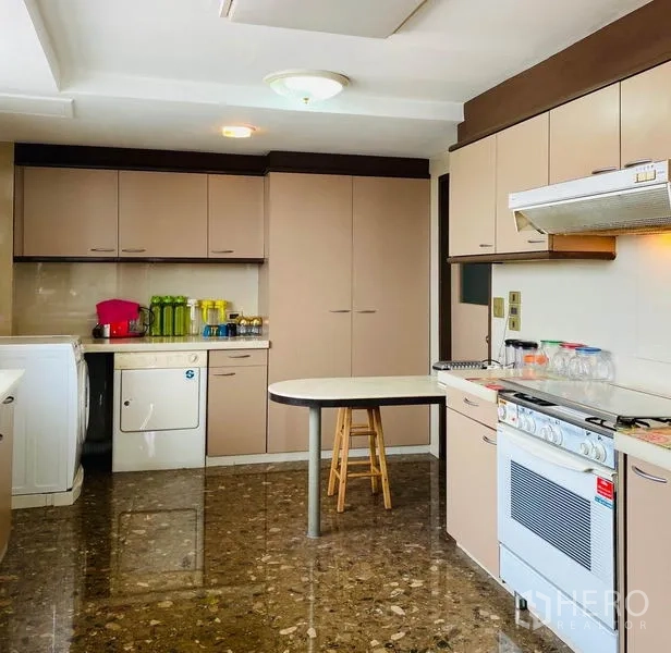 Condominium for rent in Khlong Toei, Bangkok - Spacious kitchen with oven, breakfast table and laundry appliances.