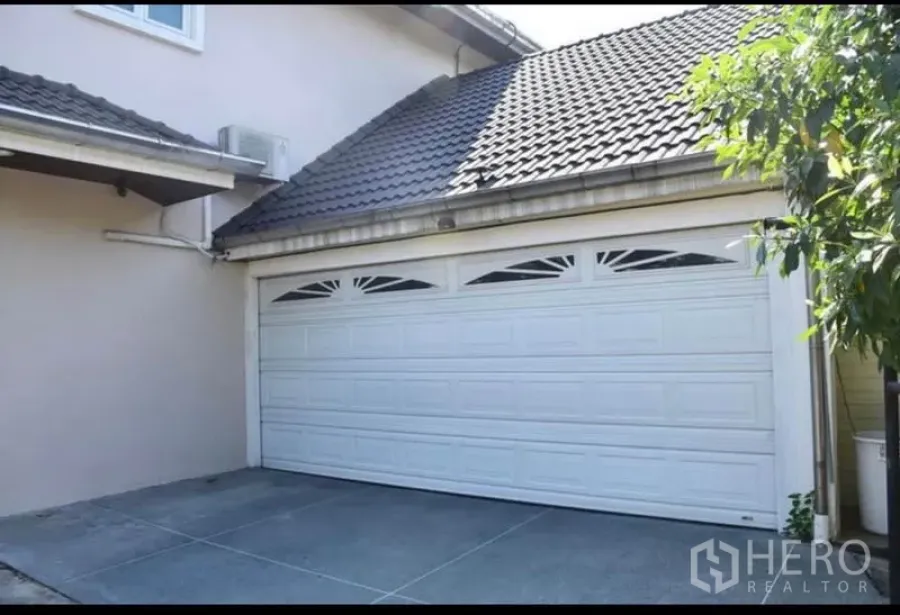 Detached House for sale in Sai Mai, Bangkok - Double garage with white sectional door under a tiled roof at a detached house in Sai Mai.