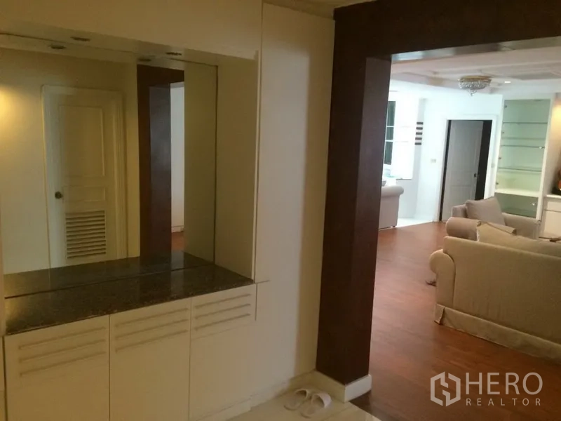 Condominium for rent in Khlong Toei, Bangkok - Entry hall with a built-in mirrored cabinet opening to a wood-floored living area.