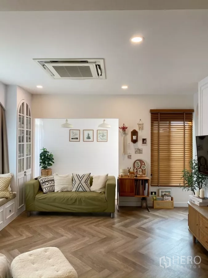 Detached House for sale in Sai Mai, Bangkok - Living room featuring a green sofa, wood blinds and herringbone floors.