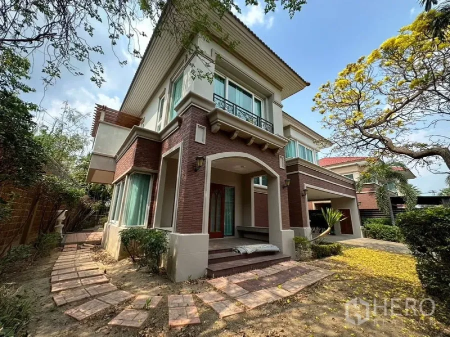 独立式住宅 出租或出售在Pak Kret, Nonthaburi - 暖武里帕克雷特两层独栋别墅，砖色外立面，前廊与花园小径。