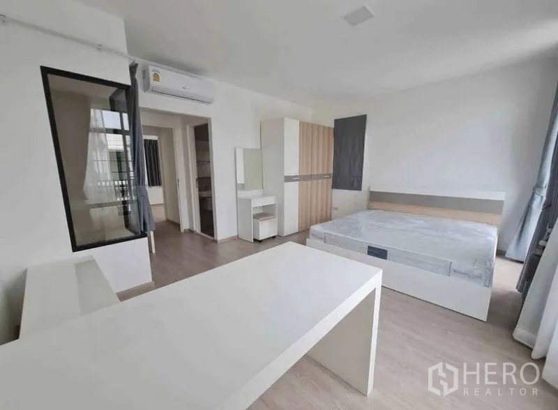 Townhouse for rent in Bang Phli, Samut Prakan - Bedroom view showing air conditioner, wardrobe, dressing table and doorway to bathroom.