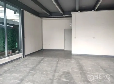 Retail Space for rent in Khlong Toei, Bangkok - Spacious shop interior with grey tiles, ceiling beams and floor-to-ceiling windows.