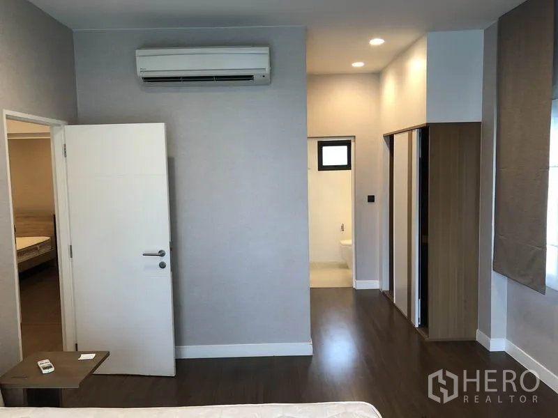 Detached House for rent in Bang Kapi, Bangkok - Upstairs bedroom with air conditioner, wardrobe, wood flooring and ensuite access.