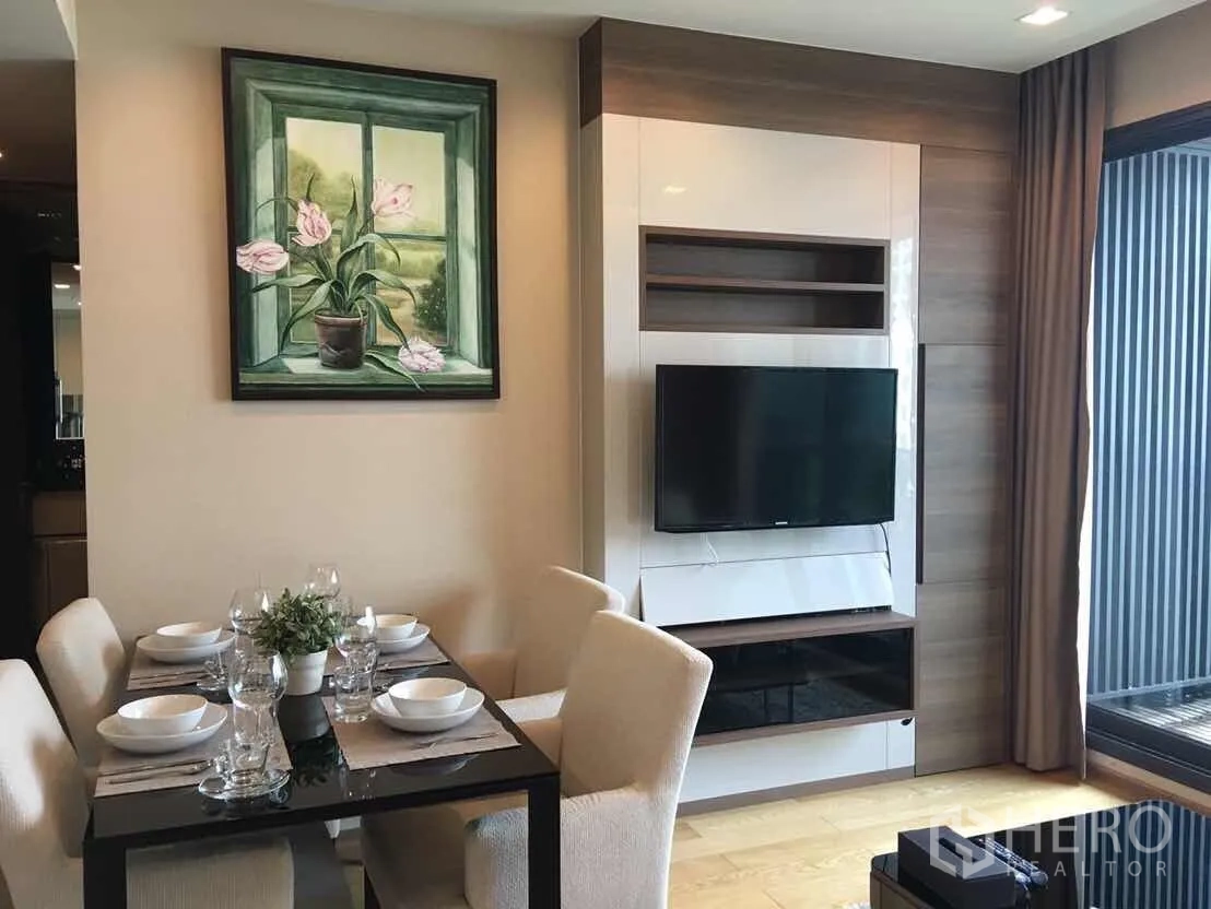 Condominium for rent or sale in Bang Rak, Bangkok - Dining area and TV wall unit opening to a balcony in a bright Silom condo