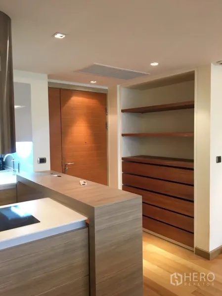 Condominium for rent in Phaya Thai, Bangkok - Compact modern kitchen with wood cabinetry, induction hob, breakfast bar and the entry door.