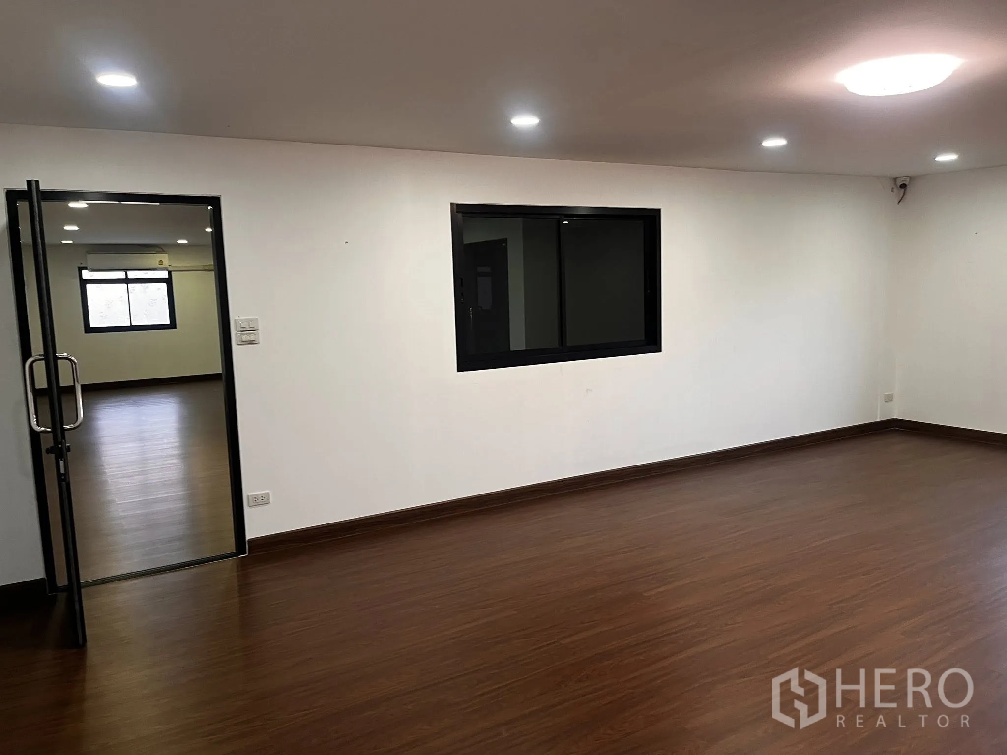 Warehouse for rent in Lat Phrao, Bangkok - Connected office rooms featuring an interior window and bright ceiling lights.