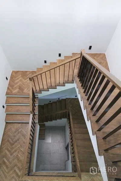 Townhouse for sale in Watthana, Bangkok - Central stairwell with wooden treads and herringbone landings viewed from above.