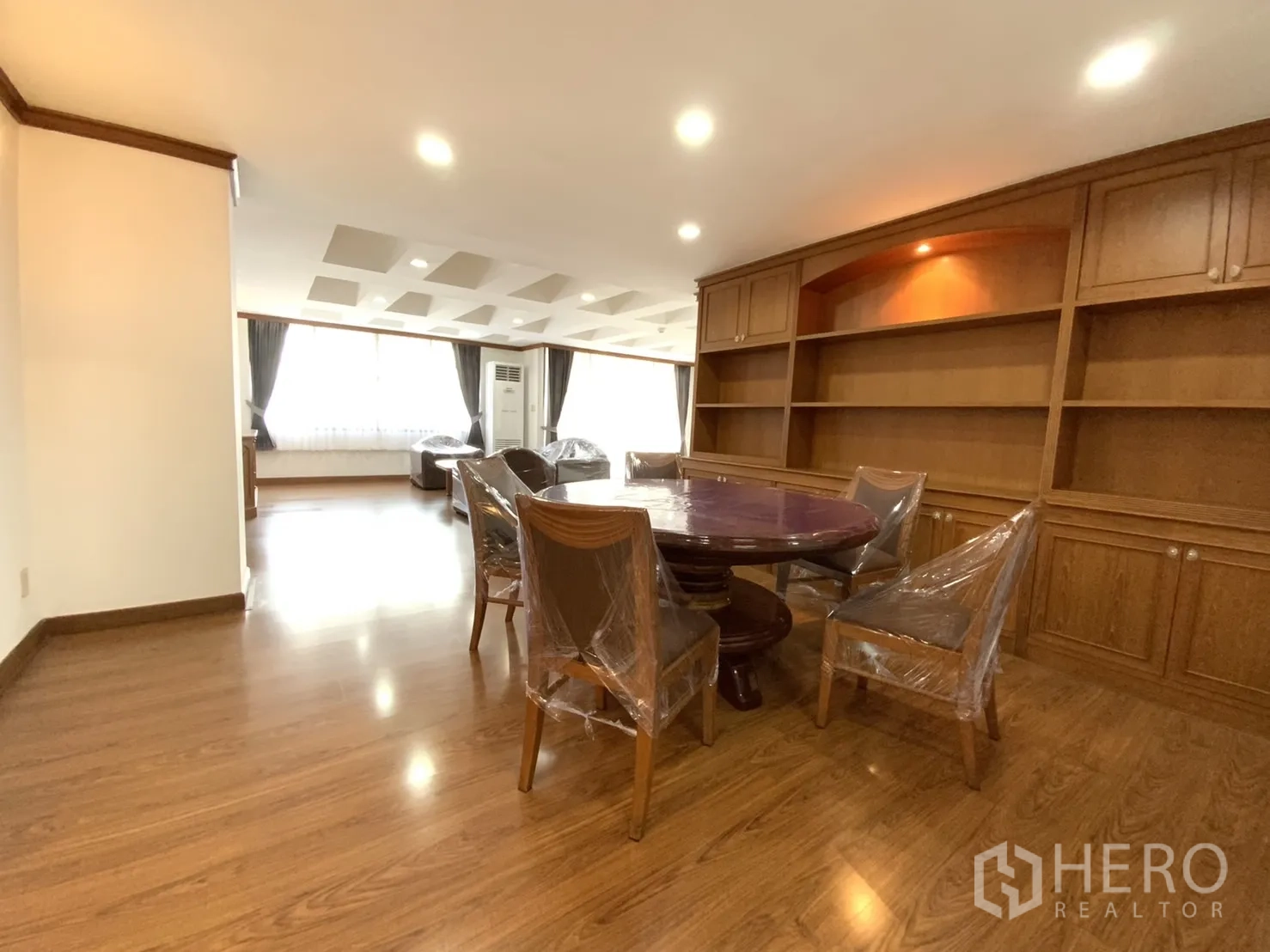 公寓 出租在Watthana, Bangkok - 餐区配圆餐桌与整面木质收纳柜，连通客厅，位于Khlong Tan Nuea。
