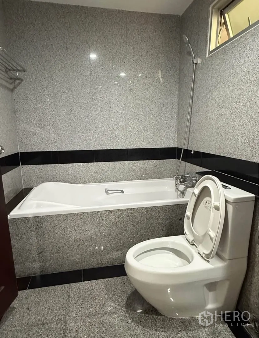 公寓 for rent in Pathum Wan, Bangkok - 花岗岩墙面卫浴，带浴缸、手持花洒与坐便器。