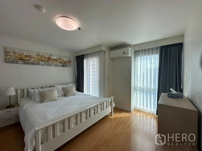 Condominium for rent or sale - Second bedroom with two walls of windows, wood floors, sheer curtains and air conditioning.