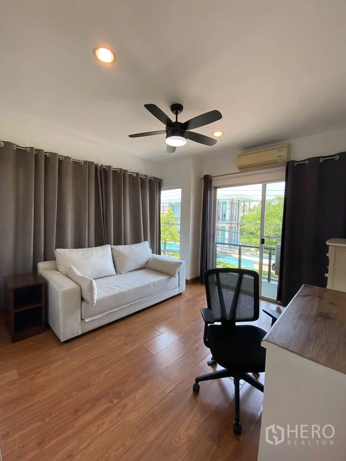独栋房屋 for rent in Mueang Samut Prakan, Samut Prakan - 拐角房另一视角，设沙发、书桌与阳台落地窗。