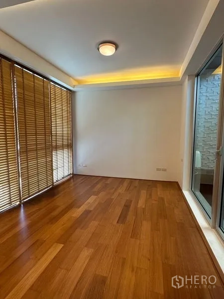 Townhouse for sale in Yan Nawa, Bangkok - Cozy bedroom with wood flooring, cove lighting and blinds opening to a small terrace.
