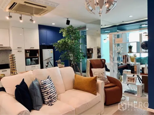 Condominium for rent in Watthana, Bangkok - Stylish living room with cream sofa, accent pillows and open shelving leading to the study.