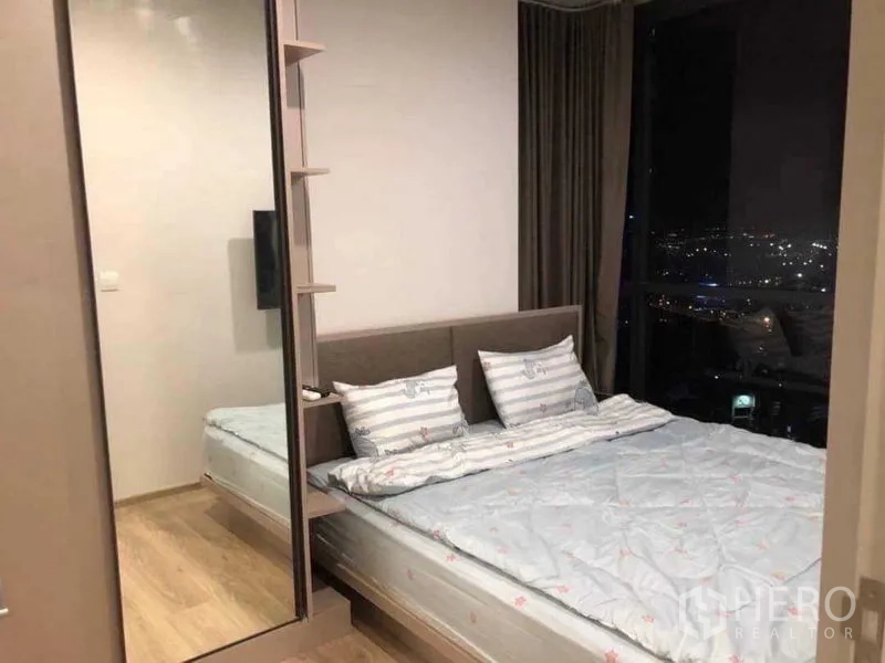 Condominium for rent in Khlong Toei, Bangkok - Master bedroom with double bed, large window, blackout curtains, and sparkling city view.