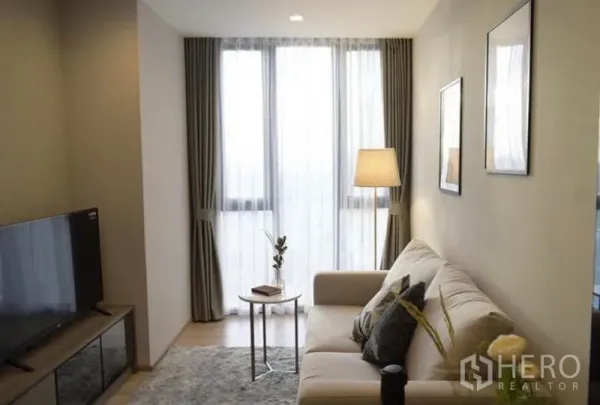 Condominium for rent or sale in Phaya Thai, Bangkok - Bright living room with sofa, TV console and floor-to-ceiling windows in a Phaya Thai condo.