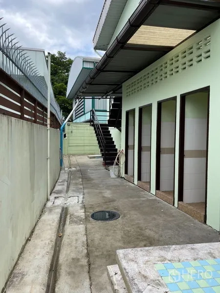 Warehouse for rent in Khan Na Yao, Bangkok - Row of staff restrooms under a canopy along the side of the building.
