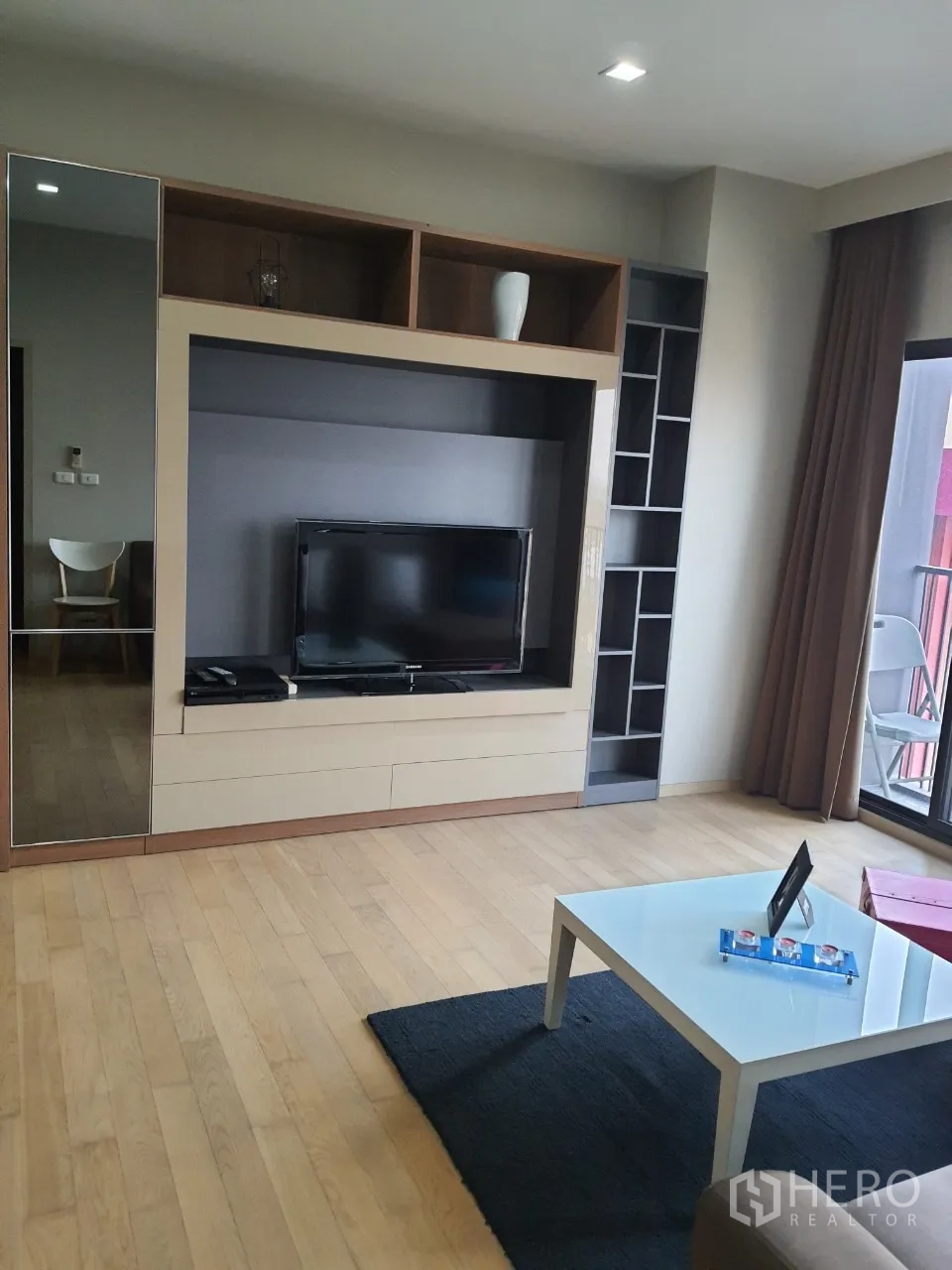 คอนโด ให้เช่าในWatthana, Bangkok - ห้องนั่งเล่นมีชั้นทีวี โต๊ะกลาง และประตูกระจกเลื่อนออกสู่ระเบียง