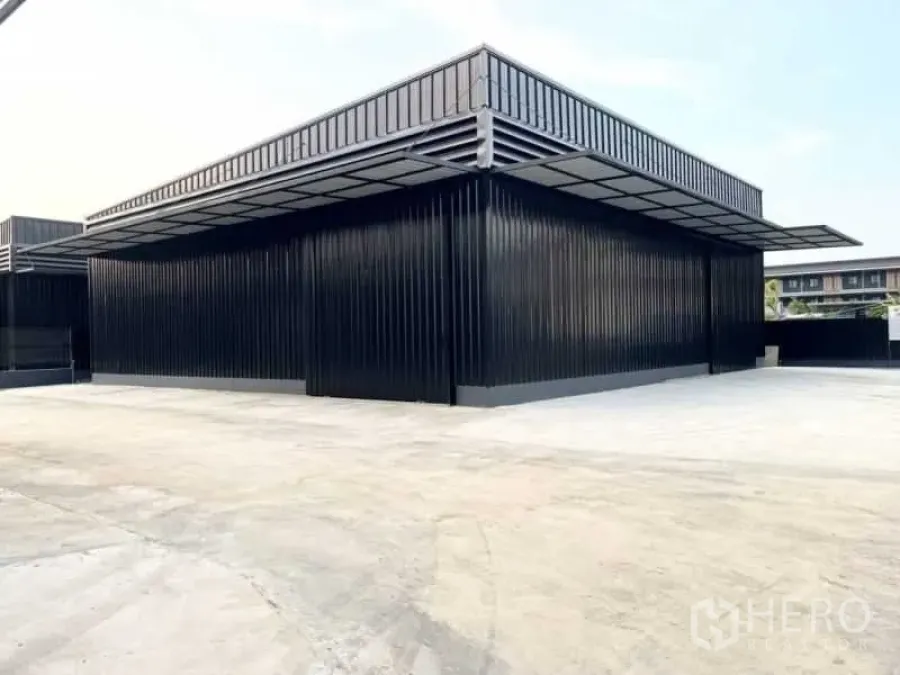 Warehouse for rent in Wang Thonglang, Bangkok - Front facade of metal-clad warehouse with wraparound awning and ample parking apron.