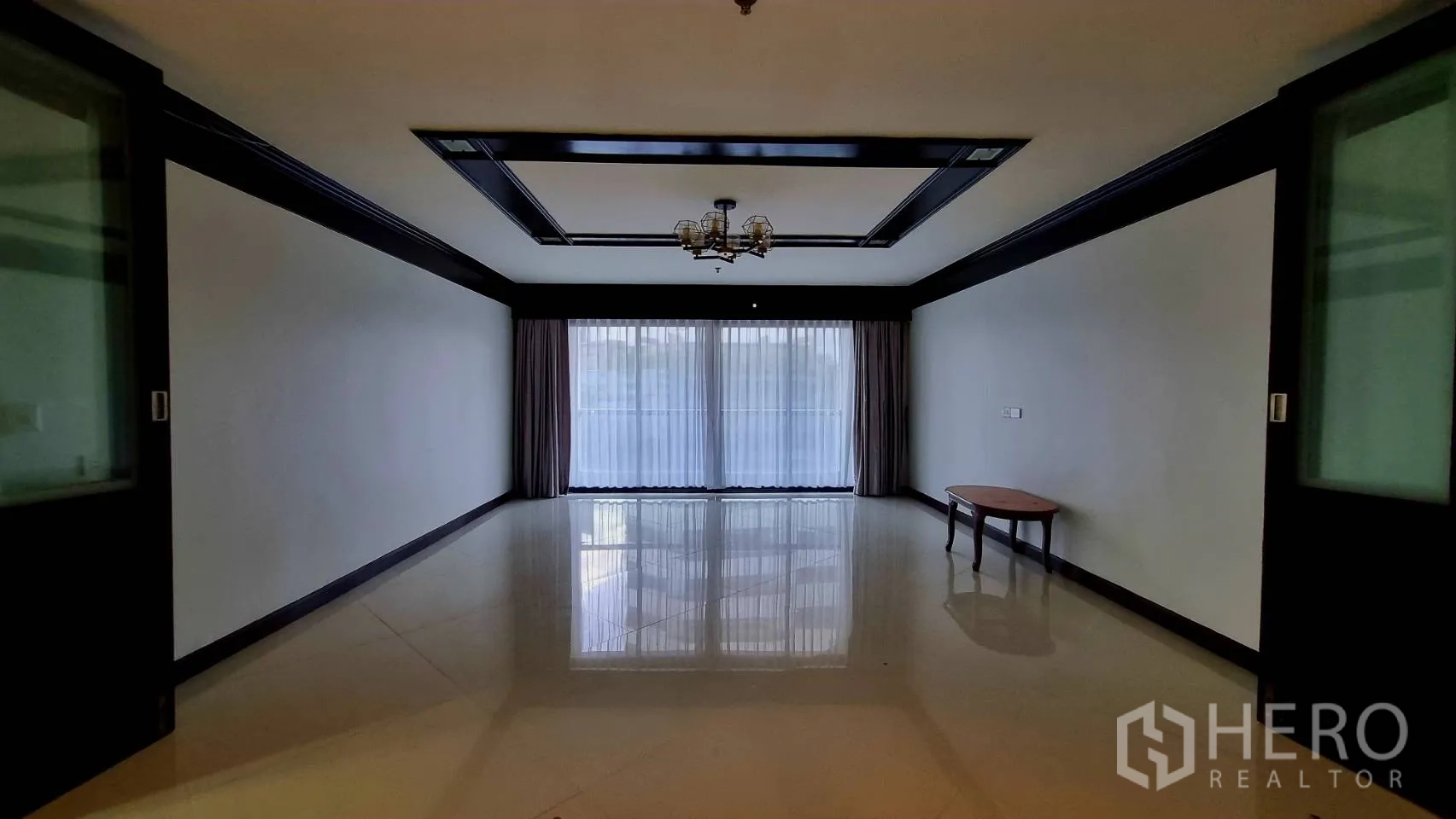 Condominium for rent in Watthana, Bangkok - Empty multipurpose room with chandelier and floor-to-ceiling curtains.