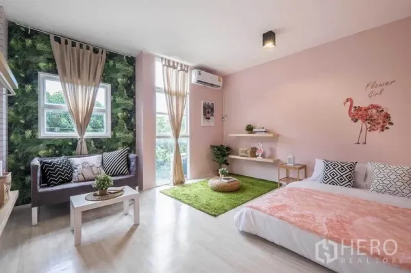 Detached House for rent in Khlong Toei, Bangkok - Airy pastel bedroom with large windows, a small sofa corner and area rug.