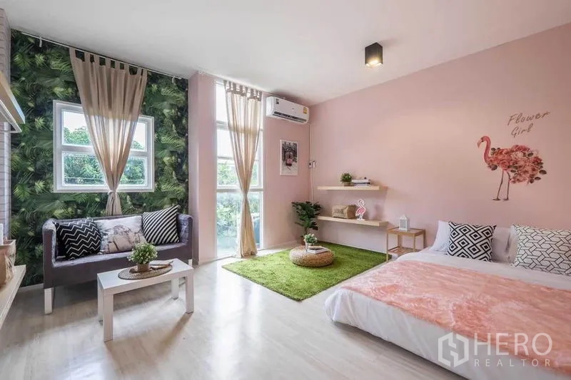 Detached House for rent in Khlong Toei, Bangkok - Airy pastel bedroom with large windows, a small sofa corner and area rug.