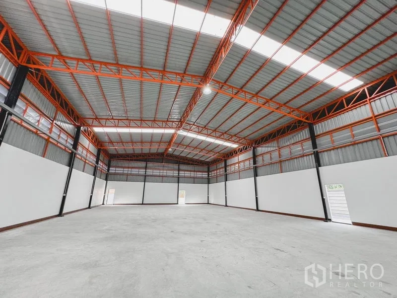 货栈 出租或出售在Khlong Luang, Pathum Thani - 仓库内部，高挑钢结构屋顶与橙色桁架，开阔的混凝土地坪。