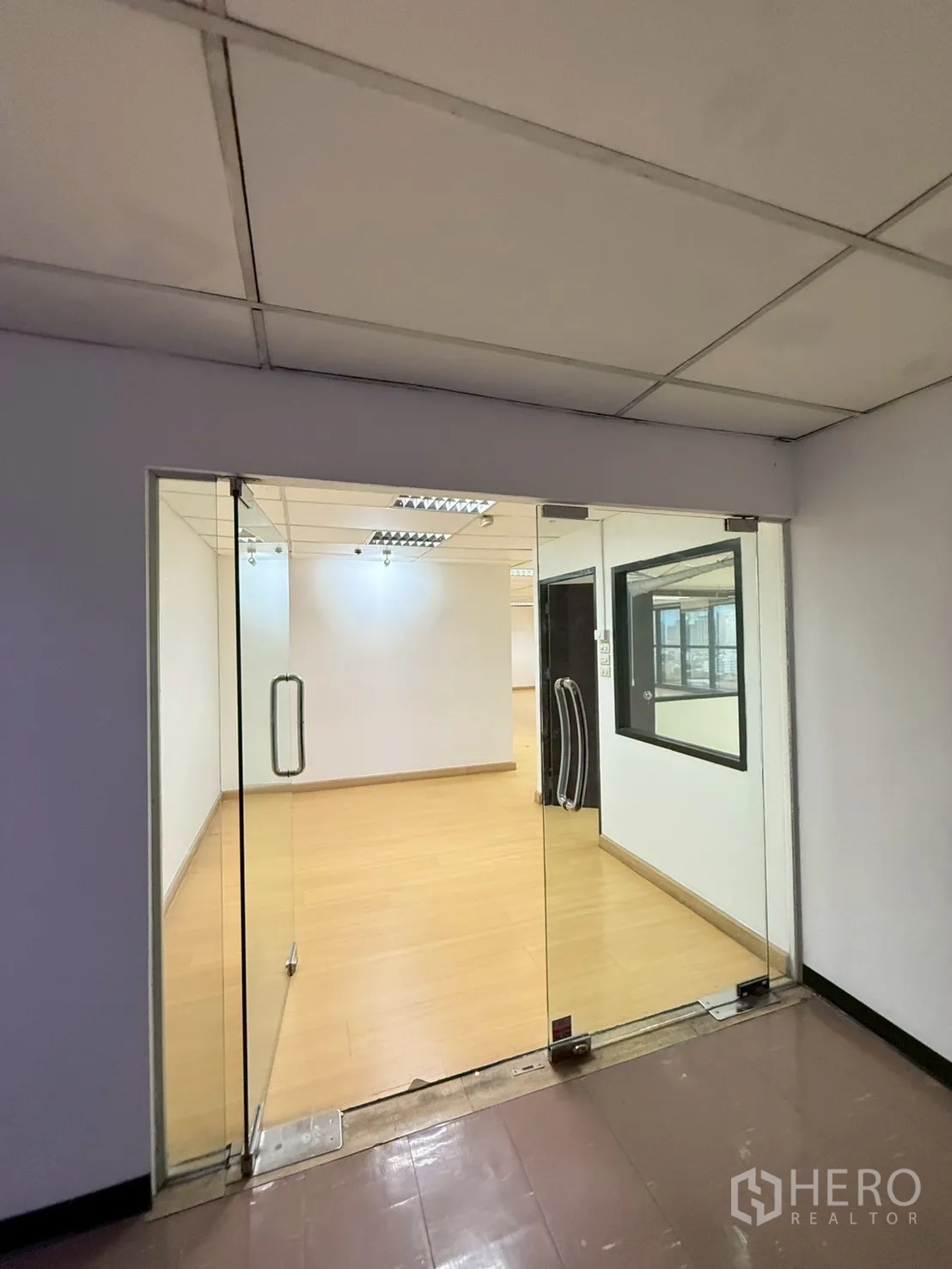 Office Space for rent in Watthana, Bangkok - Glass double-door entrance opening to a bright office with light wood floors.