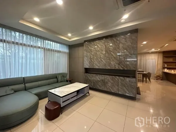 Detached House for rent in Bang Kapi, Bangkok - Bright living room with L-shaped sofa, marble feature wall and recessed ceiling lights.