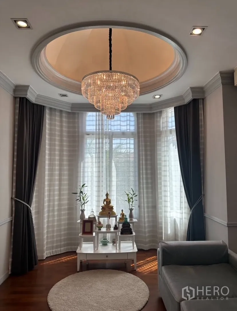 Detached House for rent or sale in Prawet, Bangkok - Close-up of a crystal chandelier above a serene alcove with tall curtained windows.