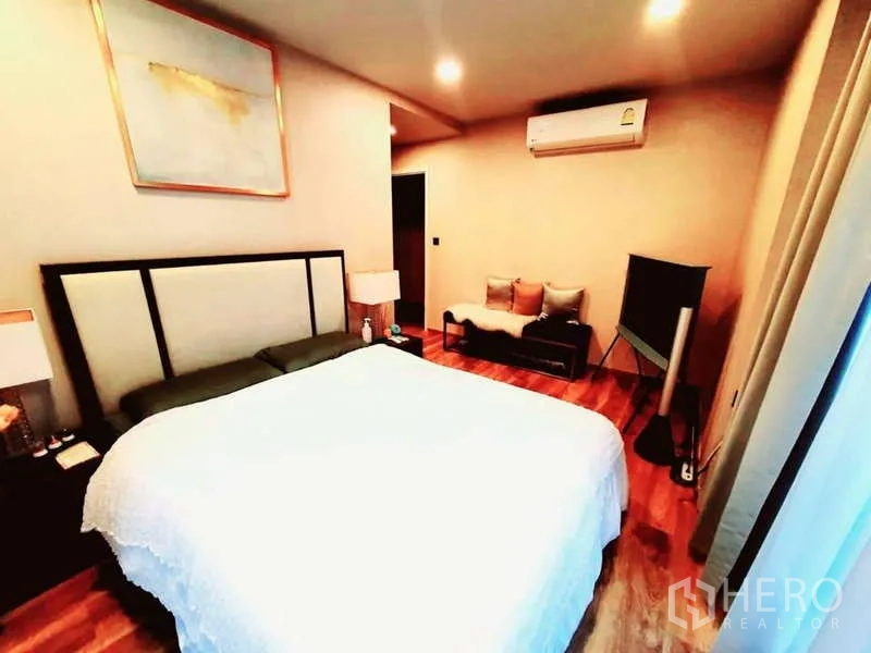 Condominium for sale in Bang Rak, Bangkok - Spacious bedroom with large bed, air conditioner, small sofa and TV stand on wood flooring.