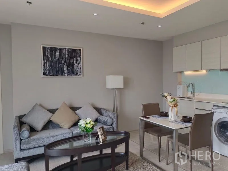 Condominium for rent in Watthana, Bangkok - Lounge and kitchenette view with under-cabinet lights and a built-in washing machine.