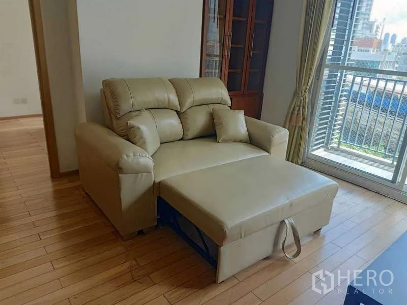 Condominium for rent in Khlong Toei, Bangkok - Convertible sofa bed extended in the lounge near the balcony.