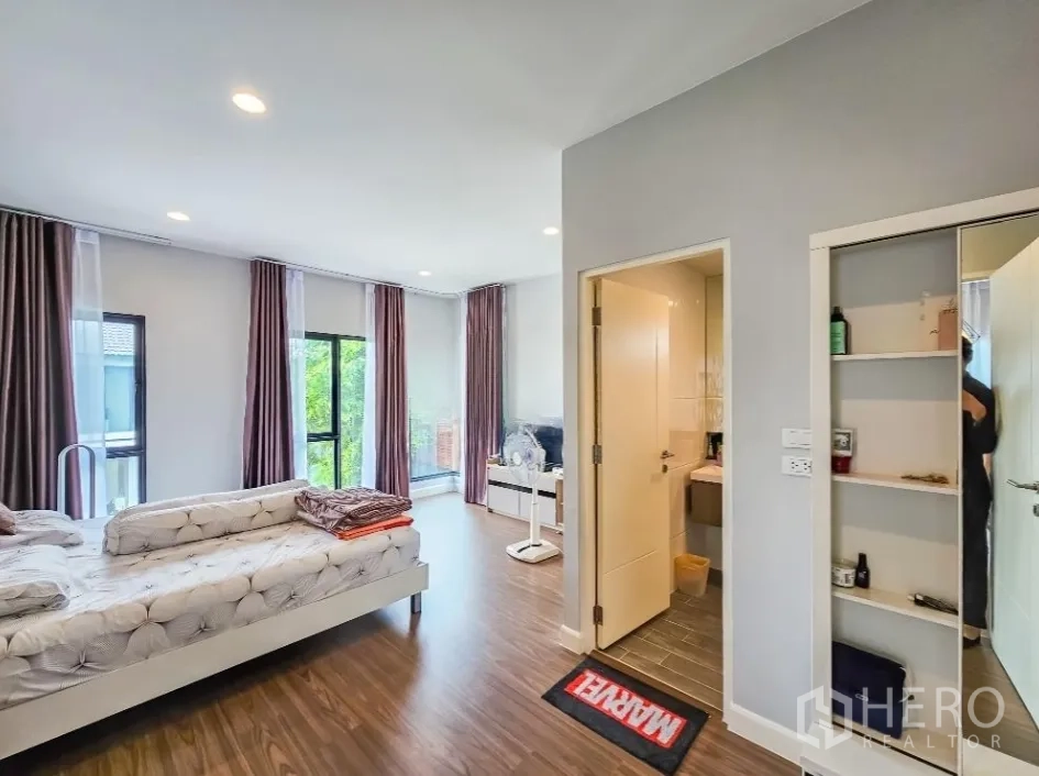 Detached House for sale in Lam Luk Ka, Pathum Thani - Large master bedroom with ensuite door, balcony access and floor-to-ceiling windows.