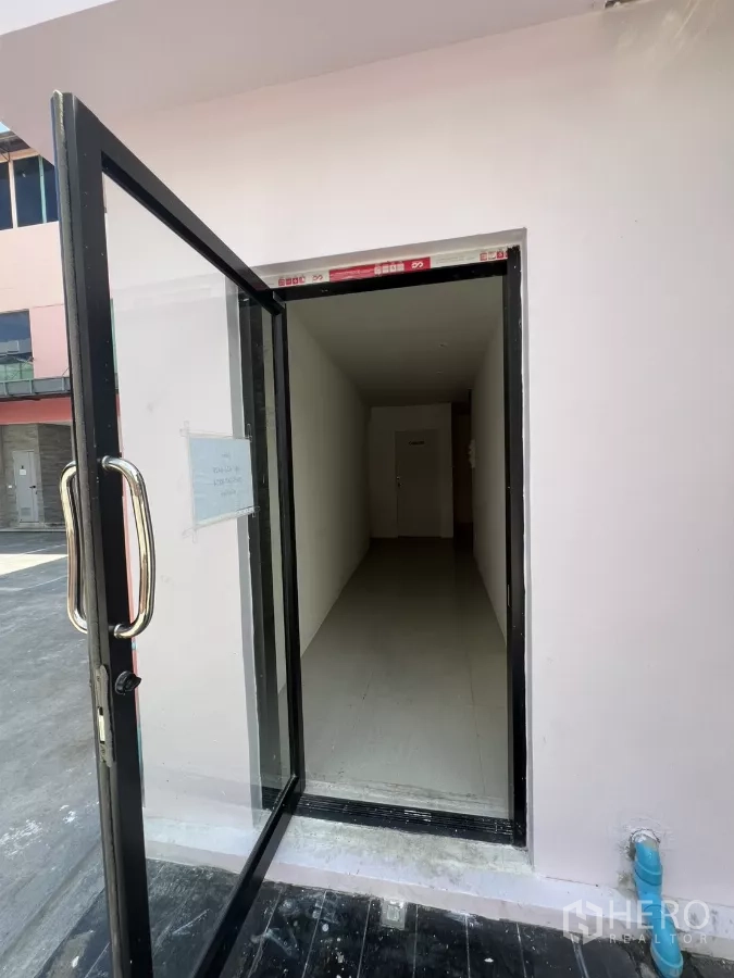 零售空间 出租 - 玻璃门入口，通向狭长的白色走道。