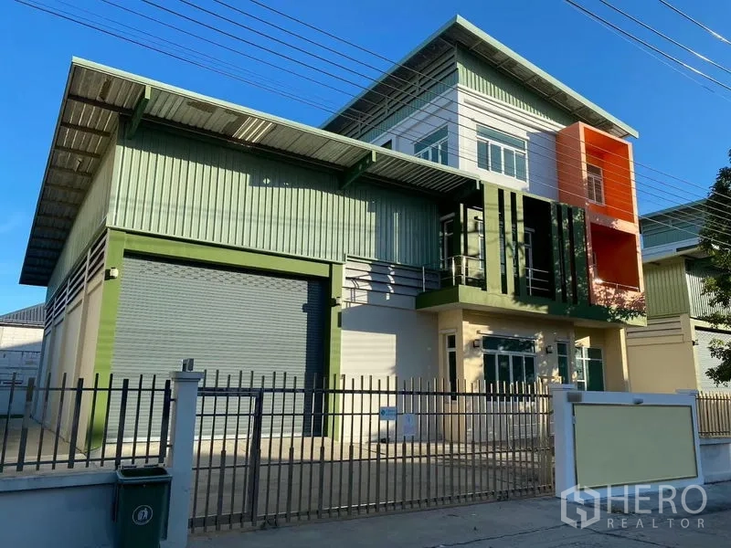 工厂 出租或出售在Lam Luk Ka, Pathum Thani - Lam Luk Ka 现代工厂外观，绿色金属板立面，宽幅卷帘门与办公楼及围栏。