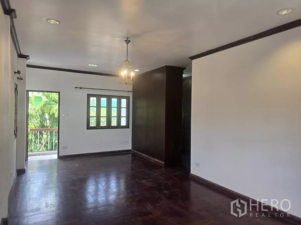 Detached House for rent in Phra Khanong, Bangkok - Walk-in closet corridor with built-in wooden wardrobes and a window.
