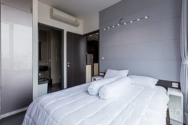 公寓 出租在Watthana, Bangkok - 温馨卧室，灰色强调墙与现代灯具，连通卫浴。