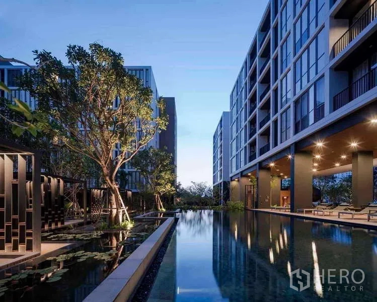 公寓 出租在Watthana, Bangkok - 傍晚的庭院泳池与现代低层楼栋。