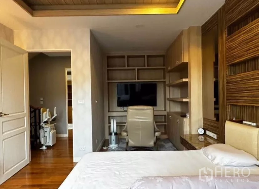 Townhouse for rent in Yan Nawa, Bangkok - Bedroom with built-in desk, shelving, and a wall-mounted TV opposite the bed.