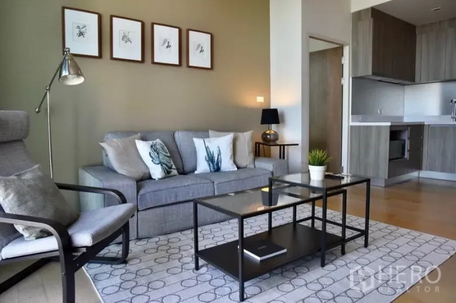 Condominium for rent in Phaya Thai, Bangkok - Bright condo living room with gray sofa, floor lamp, glass coffee table, and open kitchen in Phaya Thai near BTS Ari.
