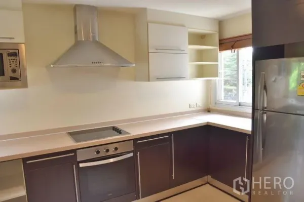 Apartment for rent in Sathon, Bangkok - Modern kitchen corner with stainless range hood and large refrigerator.