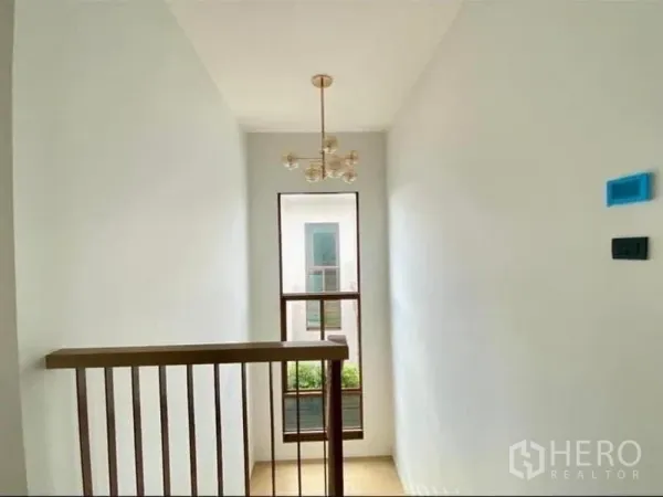 Detached House for sale in Bang Kapi, Bangkok - Staircase landing with pendant chandelier and tall window bringing in natural light.