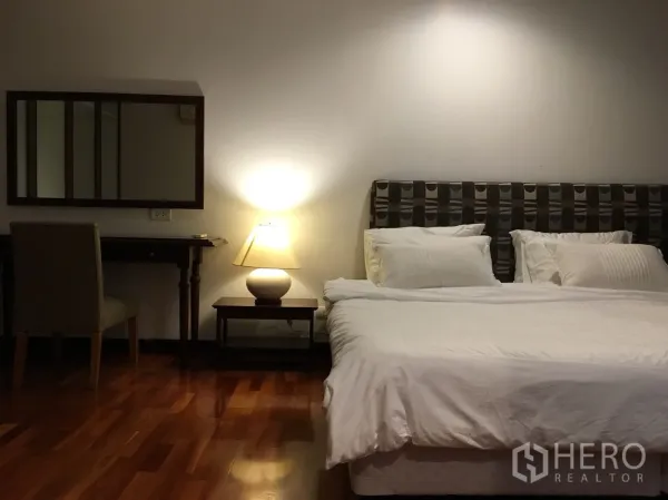 公寓 出租在Watthana, Bangkok - 主卧配大床、床头灯、梳妆台与温润木地板。