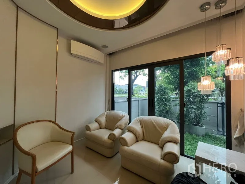 Detached House for rent in Saphan Sung, Bangkok - Cozy sitting room with armchairs, pendant lights and sliding doors to a small garden.