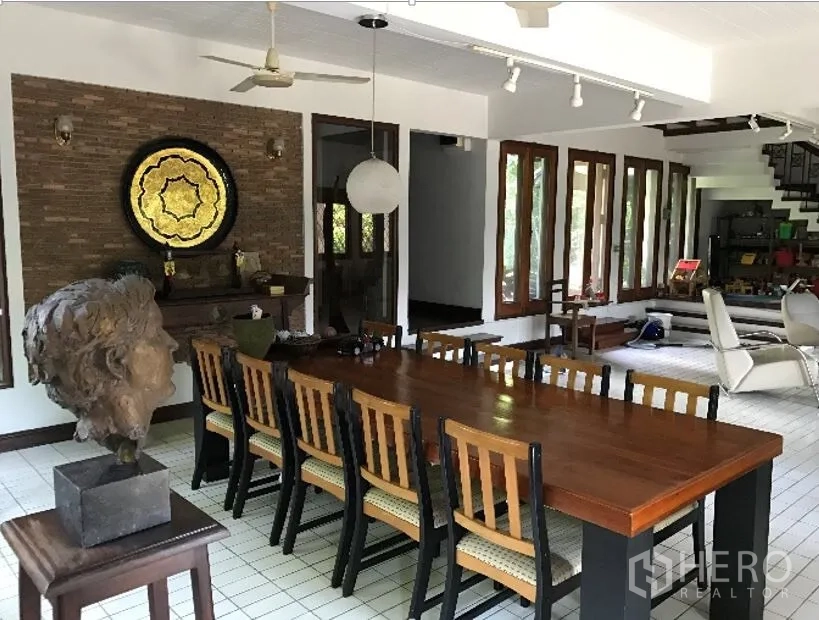 独立式住宅 出租在Khlong Toei, Bangkok - 宽敞餐厅，长木餐桌、砖砌装饰墙与轨道灯。