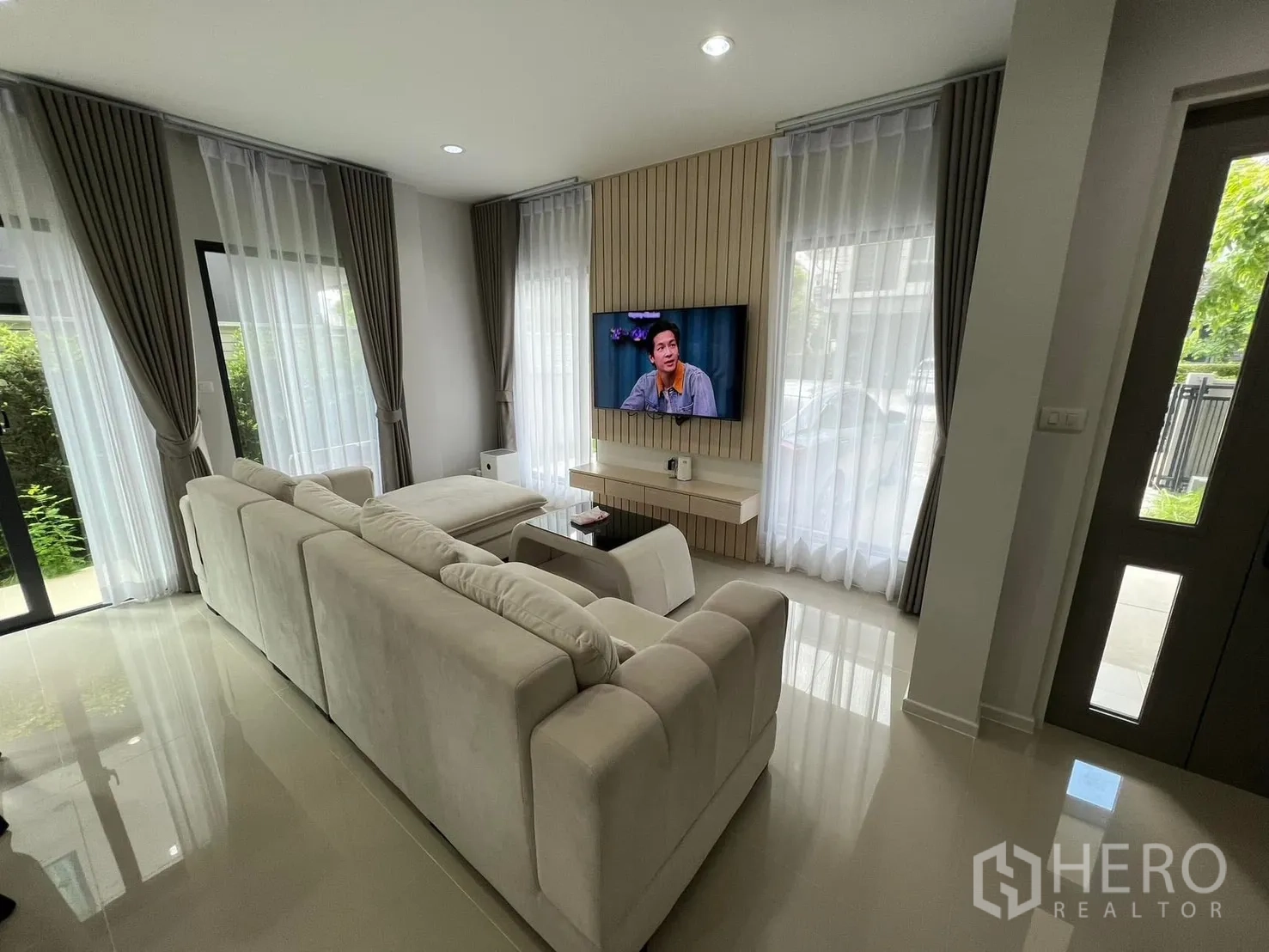 บ้านแฝด for rent in Saphan Sung, Bangkok - ห้องนั่งเล่นพร้อมทีวีติดผนัง โซฟาขนาดใหญ่ และผ้าม่านโปร่ง