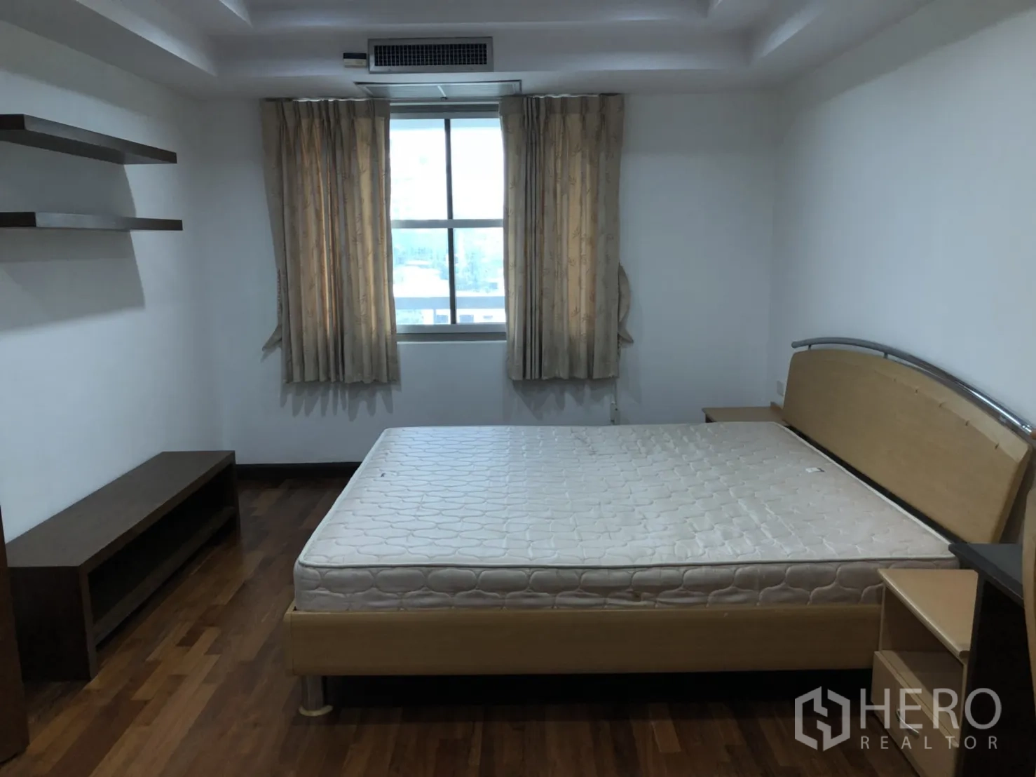 Condominium for rent in Watthana, Bangkok - Bedroom with large window, wall shelves and wood flooring.