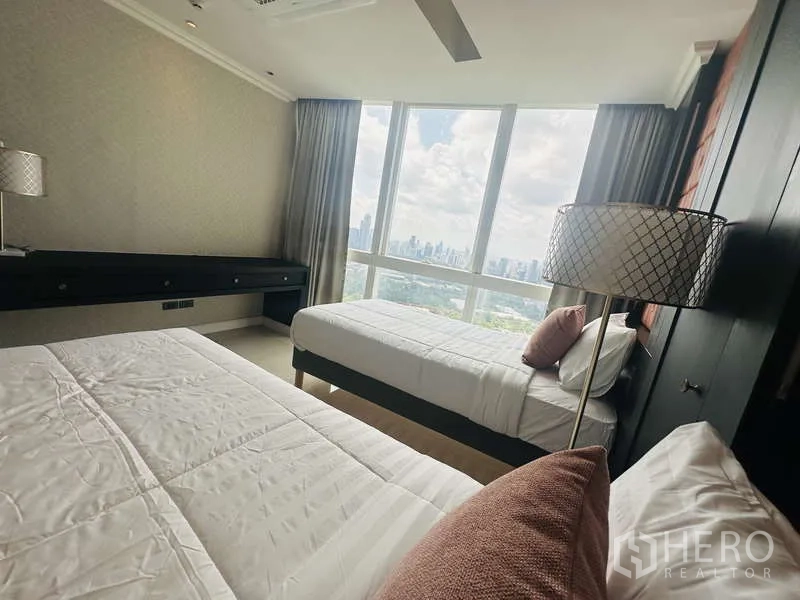 Condominium for rent or sale in Khlong Toei, Bangkok - Bright twin bedroom with two single beds and expansive skyline and park views through large windows.