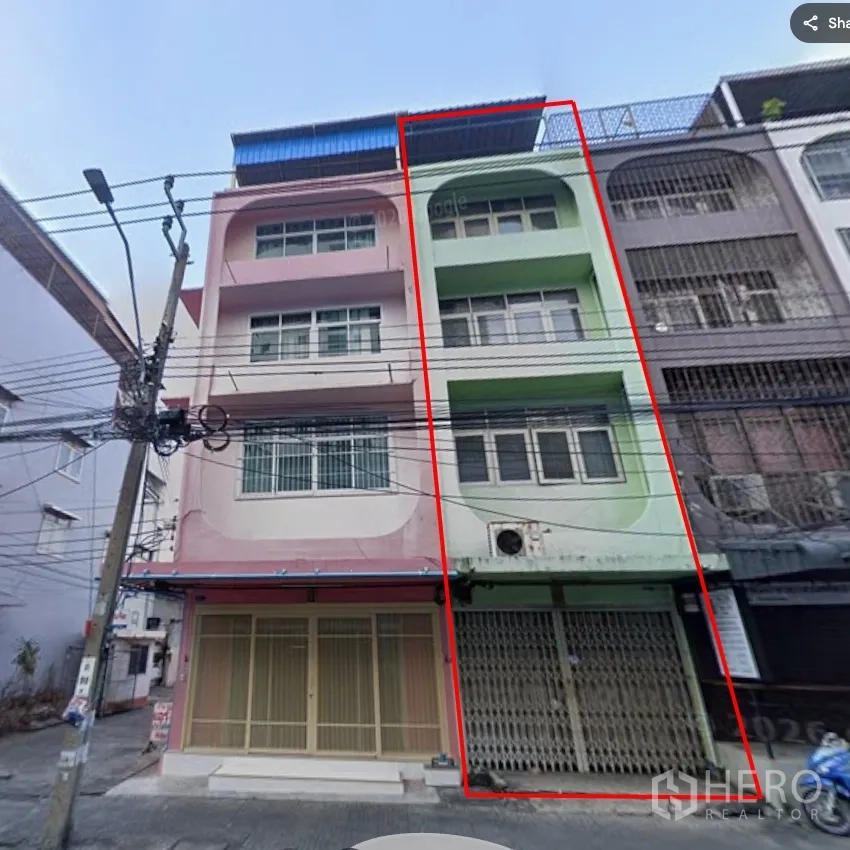 Shophouse for rent in Khlong Toei, Bangkok - Four-storey shophouse exterior with metal roller shutter frontage and balconies.
